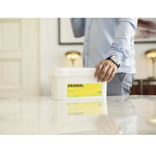 Kbelík interiérové barvy Abamal na stole s osobou v pozadí