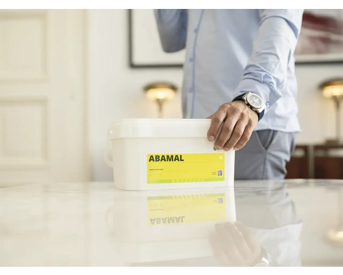 Kbelík interiérové barvy Abamal na stole s osobou v pozadí