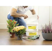 Muž otevírá nádobu s přípravkem na ochranu rostlin vedle rostlin a zahradního nářadí.