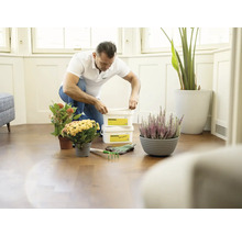 Muž klečí na podlaze s květináči a rostlinným granulátem Abamal