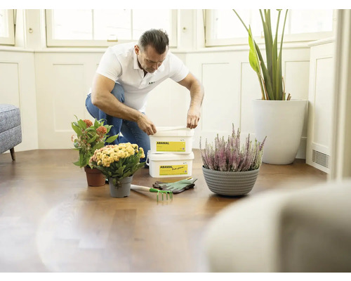 Muž klečí na podlaze s květináči a rostlinným granulátem Abamal