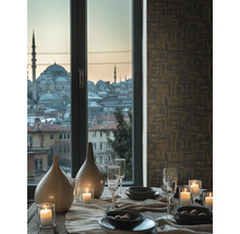 Dekorativní jídelní stůl s nádobím, sklenicemi, svíčkami a vázami před oknem s výhledem na město.