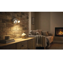 Obývací pokoj s cihlovou zdí, komodou a dvouramenným nástěnným svítidlem