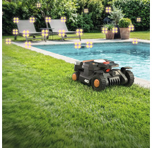 Scéna s robotickou sekačkou na trávníku vedle bazénu, lehátky a rostlinami