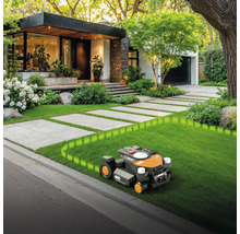Robotická sekačka v provozu před moderním domem s upravenou zahradou