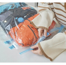 Žena uzavírá vakuový sáček s oblečením pro skladování.