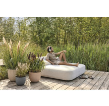 Venkovní scéna s mužem na lehátku obklopeném rostlinami v květináčích