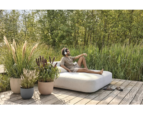 Venkovní scéna s mužem na lehátku obklopeném rostlinami v květináčích