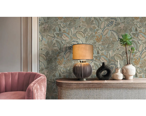 Dekorativní pokoj s květinovou tapetou, stolní lampou, růžovým křeslem a ozdobnými vázami.