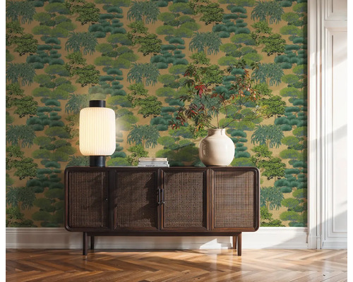 Dekorativní zelená tapeta se vzorem stromů za dřevěnou skříní v místnosti.