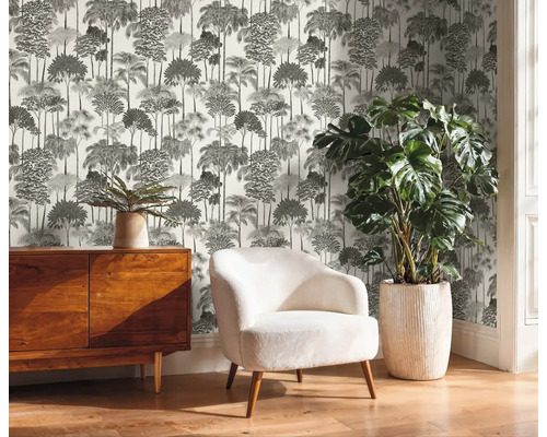 Pohled na místnost s komodou, křeslem, pokojovou rostlinou a tištěnou tapetou se vzorem stromu