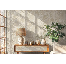 Obývací pokoj s botanickou tapetou, lampou, dekorací a rostlinou na dřevěné skříňce.