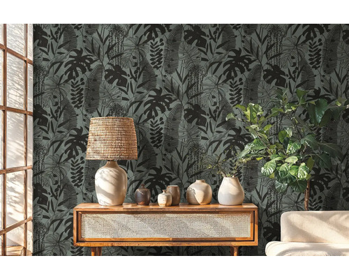 Dekorativní pokoj s tapetou s motivem tropických rostlin, lampou a rostlinami na dřevěném nábytku.