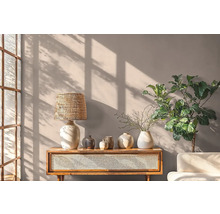 Obývací pokoj s dřevěným stolem, lampou, vázami a rostlinou před stěnou