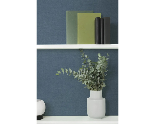 Dekorativní knihy a eukalyptus ve váze na polici.
