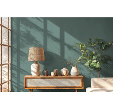 Obývací pokoj s komodou, lampou, vázami a pokojovou rostlinou před stěnou