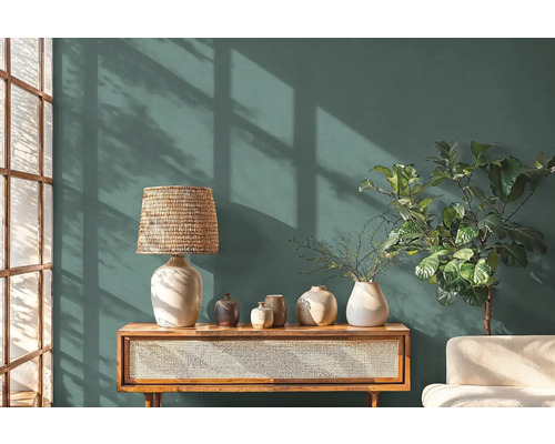 Obývací pokoj s komodou, lampou, vázami a pokojovou rostlinou před stěnou