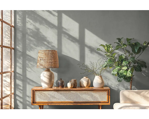 Obývací pokoj se stolní lampou, dekorací a rostlinou na dřevěné skříňce.