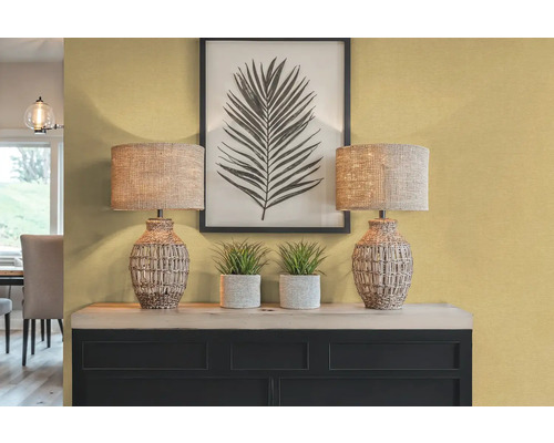 Dekorativní interiér se dvěma stolními lampami, rostlinami a zarámovaným potiskem listů na příborníku