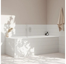 Koupelna s bílou obloženou vanou, ručníkem a dekorací