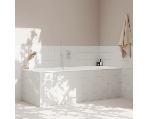 Koupelna s bílou obloženou vanou, ručníkem a dekorací