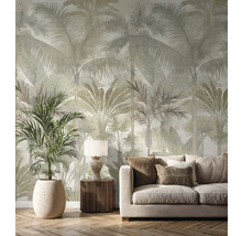 Vliesová tapeta s velkým vzorem palem ve světlém obývacím pokoji s béžovou pohovkou, dřevěným nábytkem a pokojovou rostlinou.