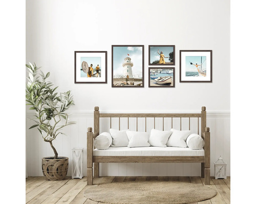 Dekorativní rámy s pobřežními motivy nad lavicí s polštáři