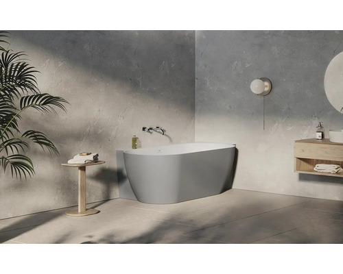 Moderní, světlá koupelna s oválnou bílou vanou, šedými stěnami s texturou, dřevěným nábytkem a minimalistickým stylem.