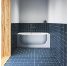 Moderní koupelna s obdélníkovou vanou ve výklenku, chromovanými armaturami, čtvercovými dlaždicemi na podlaze a stěnách a dřevěným obložením.