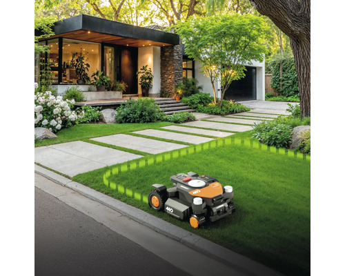 Robotická sekačka na trávníku před domem s dlážděnou cestou