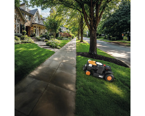 Robotická sekačka seká trávník před obytným domem.