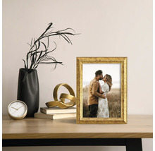 Dekorativní zlatý fotorámeček s fotografií na stole