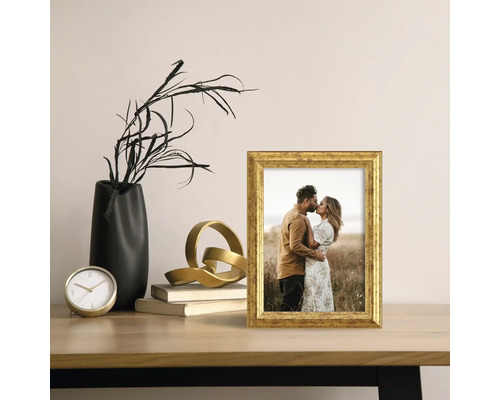 Dekorativní zlatý fotorámeček s fotografií na stole