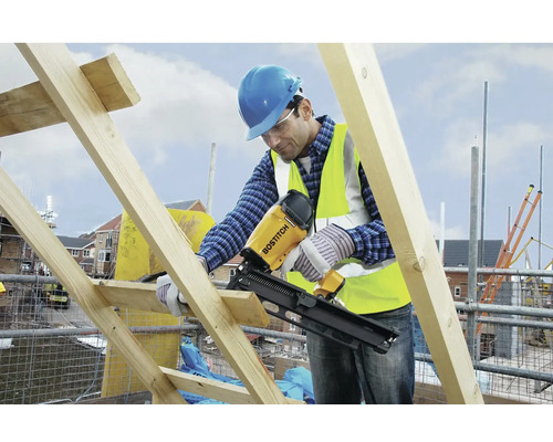 Stavební dělník používá pásovou hřebíkovačku Bostitch na staveništi.