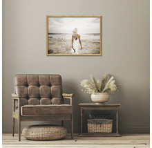 Interiér obývacího pokoje s křeslem, příručním stolkem a zarámovaným plážovým obrazem