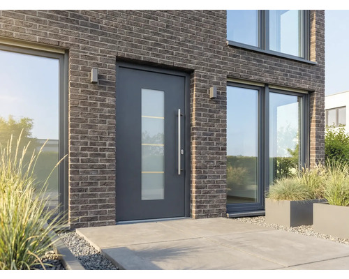 Moderní dům s vchodovými dveřmi se skleněnou vložkou, cihlovou fasádou a velkými okny