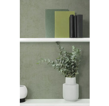 Vliesová tapeta s jemnou strukturou v tmavě zelené barvě na stěně za bílou policí s knihami a vázou s eukalyptem.