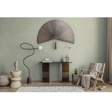 Moderně zařízený pokoj se světle zelenou barvou na stěně, velkým dekorativním vějířem, konzolovým stolkem a pleteným křeslem.