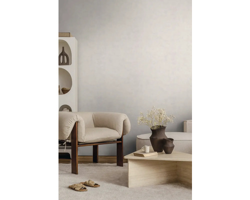 Světlý obývací pokoj se strukturovanou stěnou, moderním dřevěným křeslem, kamenným konferenčním stolkem a světlým kobercem.