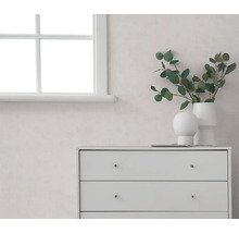 Světlý pokoj s bílým oknem, světlou stěnou a bílou komodou, zdobený vázami s eukalyptovými větvičkami.