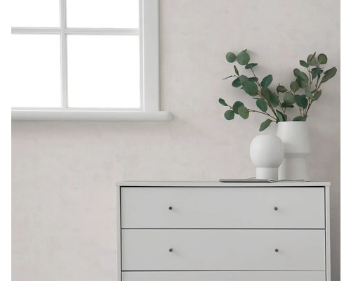 Světlý pokoj s bílým oknem, světlou stěnou a bílou komodou, zdobený vázami s eukalyptovými větvičkami.