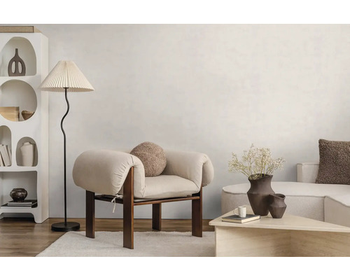 Světlý obývací pokoj v moderním stylu s dřevěným křeslem, stojací lampou s plisovaným stínidlem a bílou policí s organickými tvary.