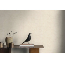 Světlá stěna se strukturovanou tapetou v minimalistické místnosti s komodou, dekorativní figurkou ptáka a kamennou vázou.