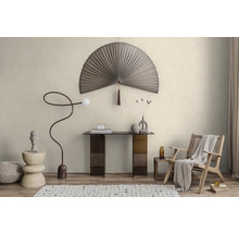 Světlý minimalistický pokoj s nástěnnou dekorací ve tvaru vějíře, skleněným stolem, prohnutou stojací lampou a dřevěným křeslem na strukturovaném koberci.