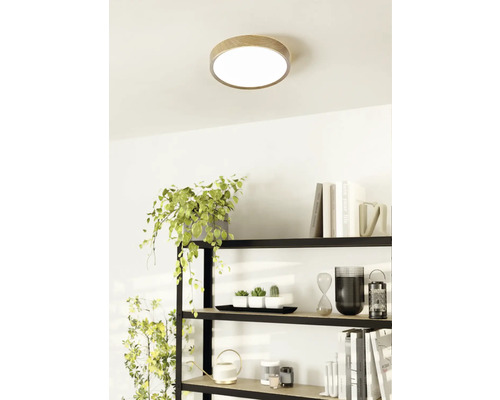 Stropní svítidlo s dřevěným okrajem ve světlé místnosti nad policí.