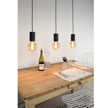 Scéna se třemi závěsnými světly nad jídelním stolem s nádobím a nápoji