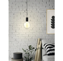 Závěsná lampa s Edisonovou žárovkou před cihlovou zdí