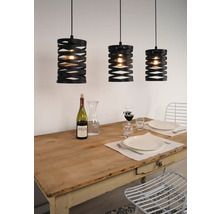 Tři černé závěsné lampy nad prostřeným jídelním stolem.