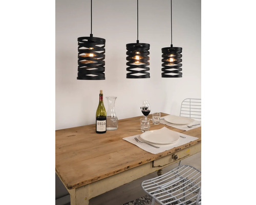 Tři černé závěsné lampy nad prostřeným jídelním stolem.