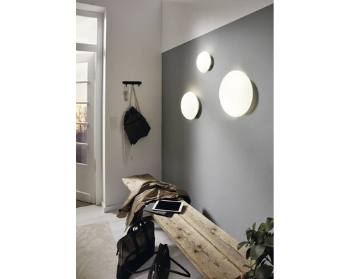 Světlý vstupní prostor s dřevěnou stoličkou, nástěnnými svítidly a věšákem